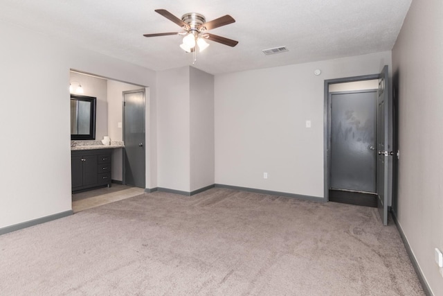 unfurnished bedroom featuring ceiling fan, light colored carpet, and connected bathroom