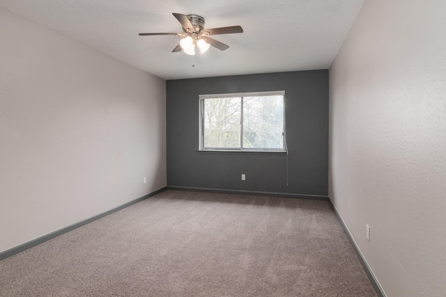 unfurnished room with a textured ceiling, dark carpet, and ceiling fan