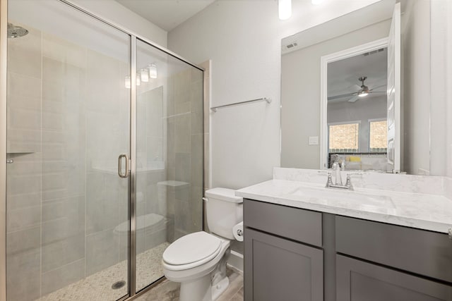 bathroom featuring vanity, toilet, ceiling fan, and a shower with shower door