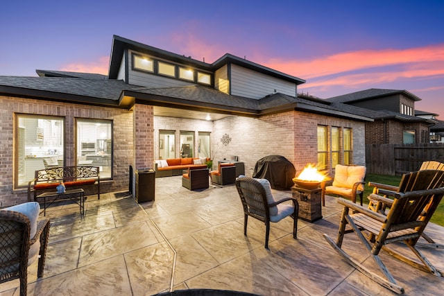 back house at dusk with a patio area and an outdoor living space with a fire pit