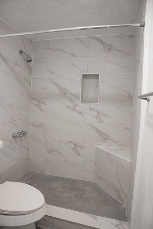 bathroom featuring toilet and tiled shower