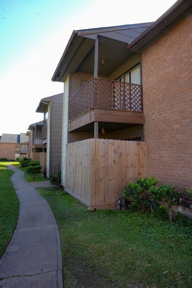 view of side of home with a balcony and a lawn