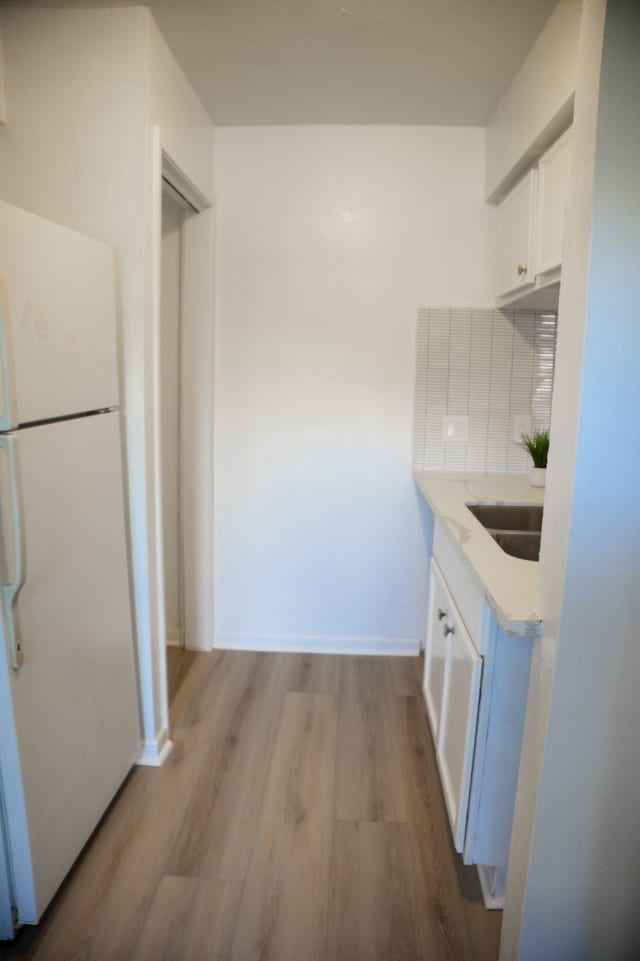 kitchen with white cabinets, sink, light hardwood / wood-style flooring, tasteful backsplash, and white fridge