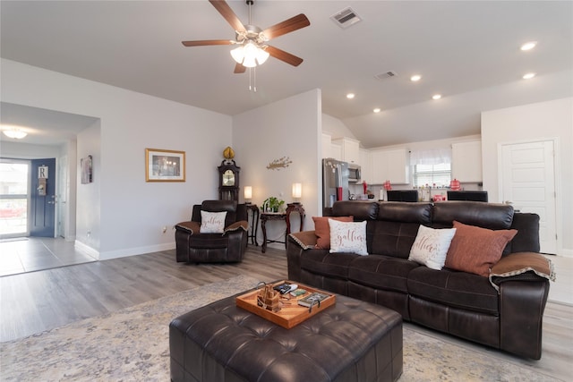 living room with ceiling fan, lofted ceiling, and light hardwood / wood-style flooring