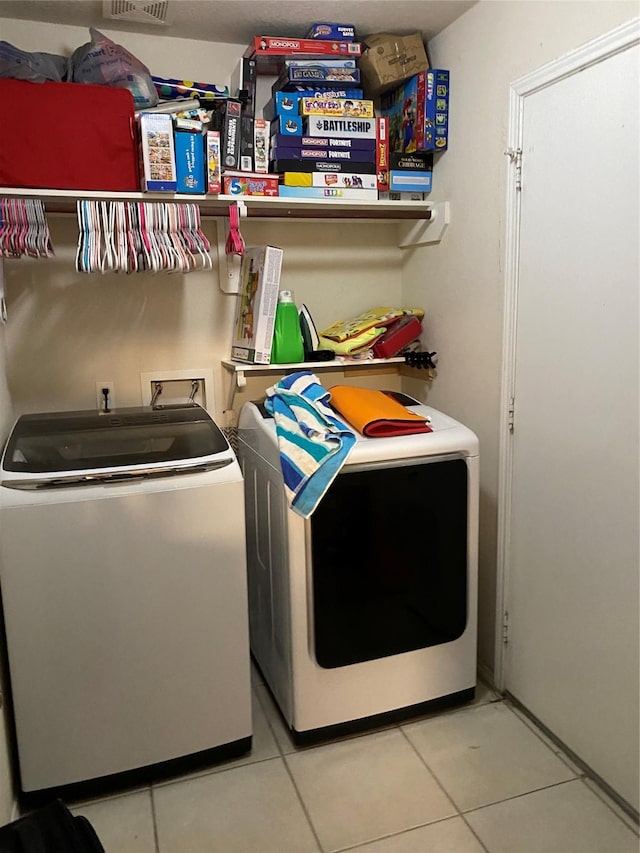 washroom featuring washing machine and dryer and tile patterned flooring