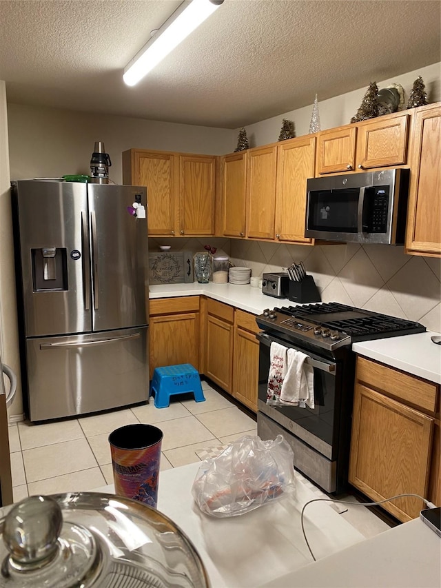 kitchen featuring a textured ceiling, light tile patterned flooring, backsplash, and appliances with stainless steel finishes