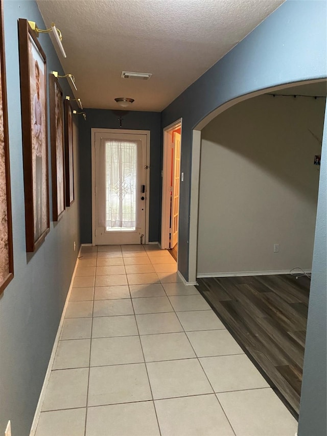 hall featuring light tile patterned floors and a textured ceiling