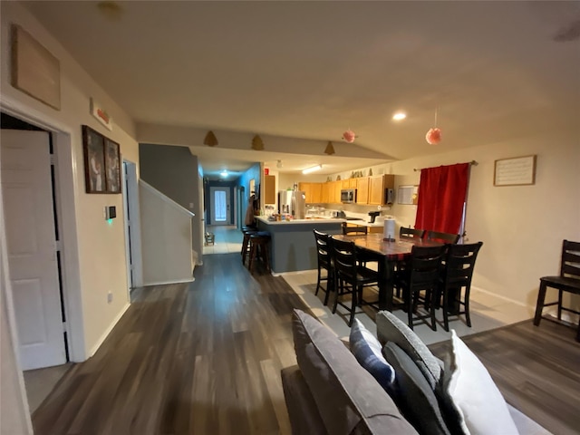 dining room featuring vaulted ceiling and dark wood-type flooring