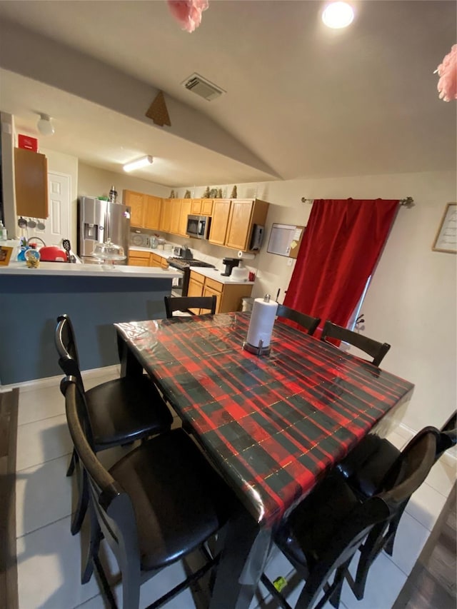 tiled dining area featuring vaulted ceiling