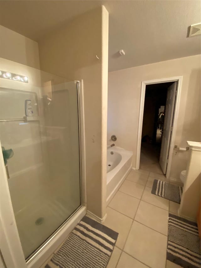 bathroom with tile patterned floors, toilet, and shower with separate bathtub