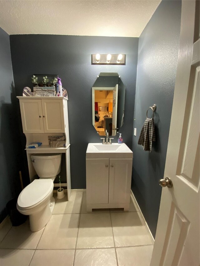 bathroom with tile patterned flooring, vanity, toilet, and a textured ceiling