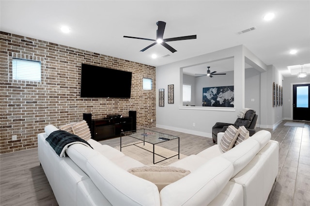 living area featuring baseboards, brick wall, visible vents, and wood finished floors