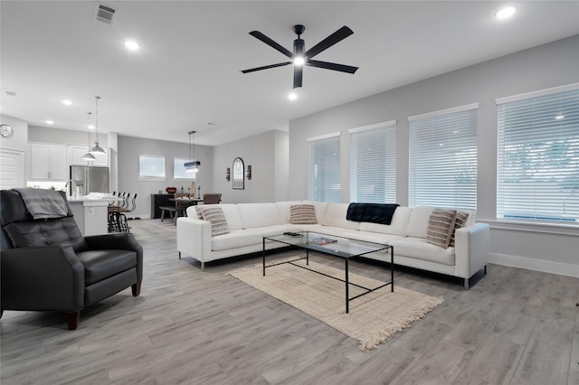 living area featuring light wood-type flooring, a healthy amount of sunlight, visible vents, and recessed lighting