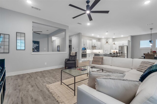 living room featuring ceiling fan and light hardwood / wood-style flooring