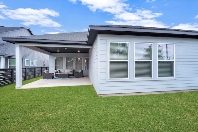 rear view of property with a shingled roof, fence, an outdoor living space, a yard, and a patio area