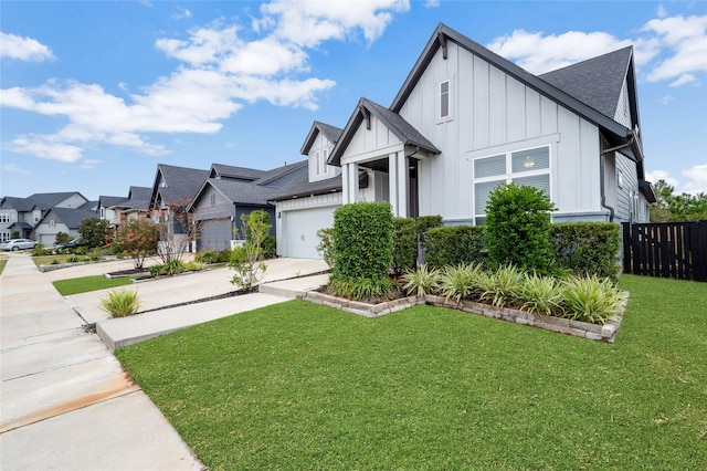 modern farmhouse with a shingled roof, fence, driveway, board and batten siding, and a front yard