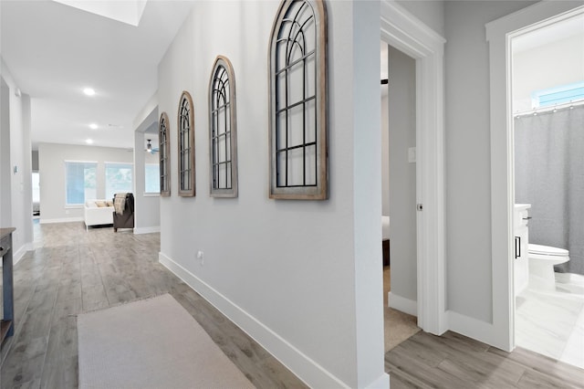 hall featuring baseboards, wood finished floors, and recessed lighting