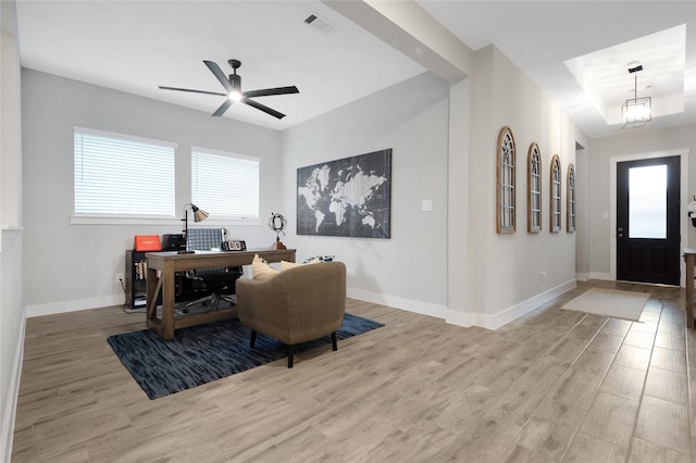 home office with baseboards, visible vents, light wood finished floors, and ceiling fan with notable chandelier