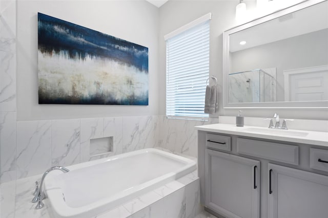 bathroom with a wealth of natural light, a stall shower, a garden tub, and vanity