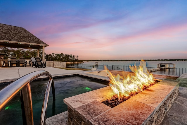 dock area with a fire pit, a patio area, and a water view