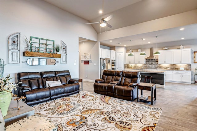 living room with lofted ceiling, sink, ceiling fan, and light wood-type flooring