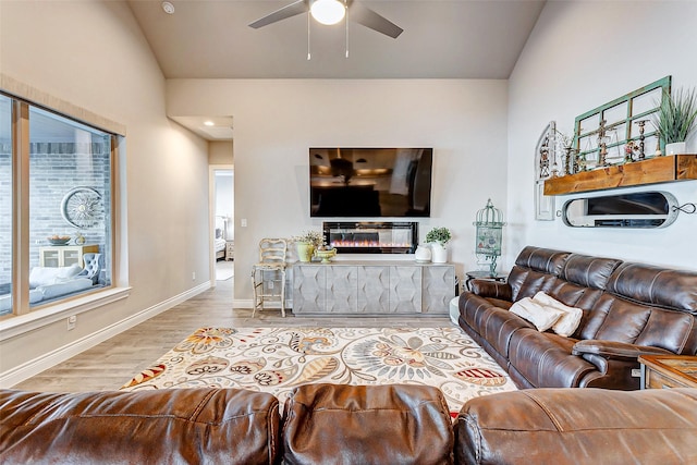 living room featuring ceiling fan, lofted ceiling, and light wood-type flooring