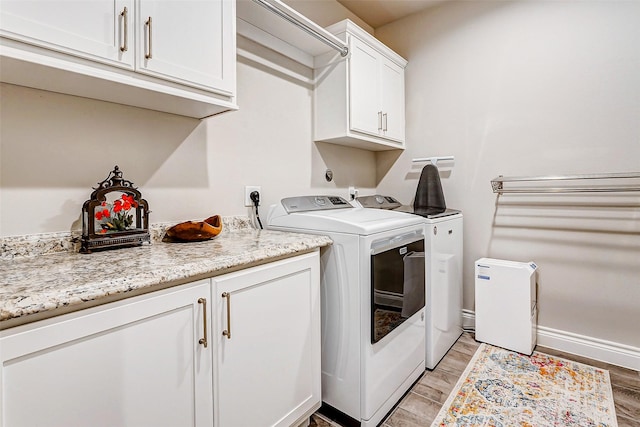 laundry area featuring cabinets, washing machine and dryer, and light wood-type flooring