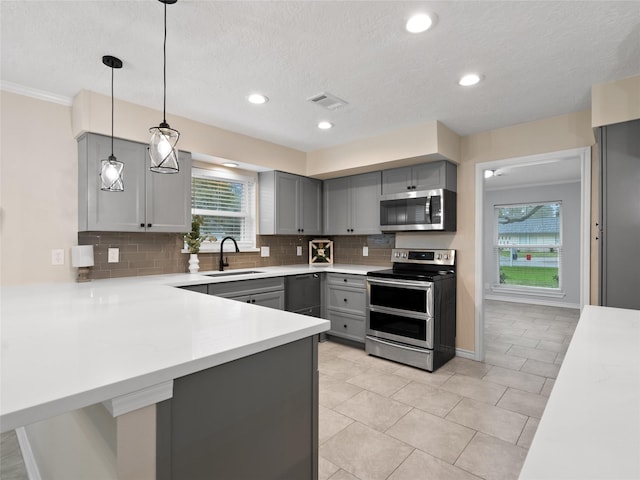 kitchen with gray cabinets, appliances with stainless steel finishes, decorative light fixtures, sink, and kitchen peninsula