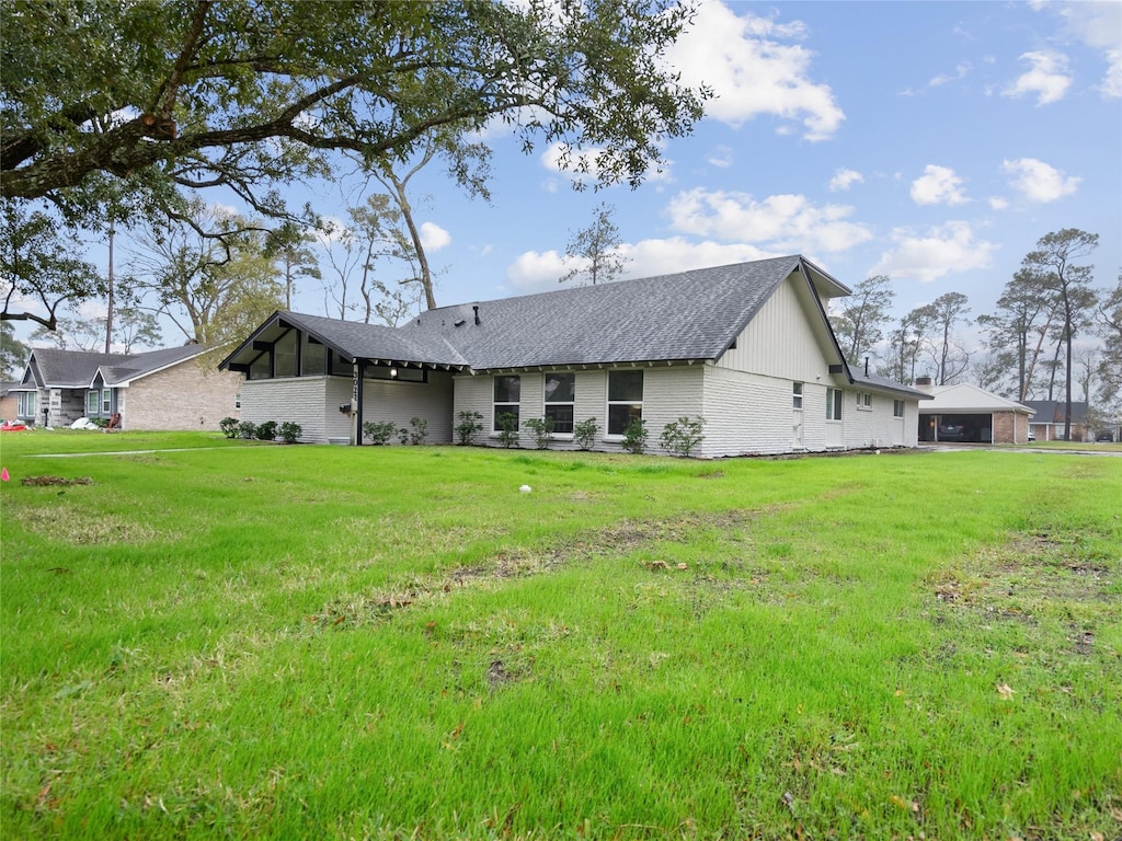 back of house featuring brick siding and a lawn