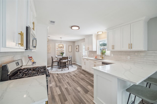 kitchen with pendant lighting, a breakfast bar, light stone counters, white cabinets, and white gas stove