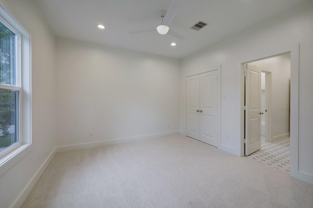 unfurnished bedroom featuring ceiling fan, light carpet, and a closet