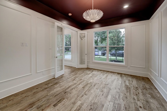 unfurnished room featuring light wood-type flooring and a notable chandelier