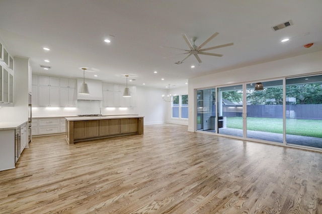 kitchen featuring pendant lighting, white cabinets, a spacious island, and light hardwood / wood-style floors