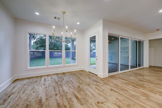 unfurnished dining area featuring light hardwood / wood-style floors and an inviting chandelier