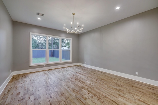 spare room with light wood-type flooring and an inviting chandelier