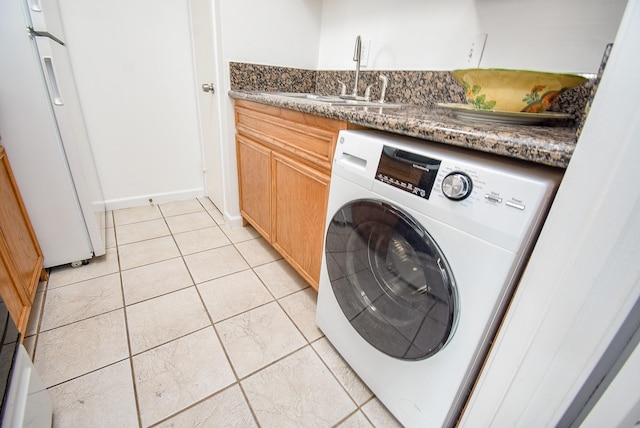 clothes washing area featuring cabinets, light tile patterned floors, washer / clothes dryer, and sink