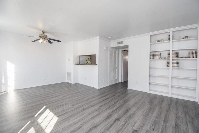 unfurnished living room with ceiling fan, crown molding, and dark wood-type flooring