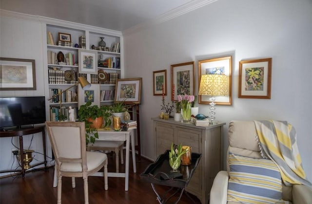 sitting room with built in shelves, crown molding, and dark wood-type flooring