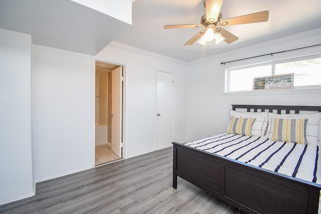 bedroom featuring hardwood / wood-style flooring, ensuite bath, ceiling fan, and crown molding