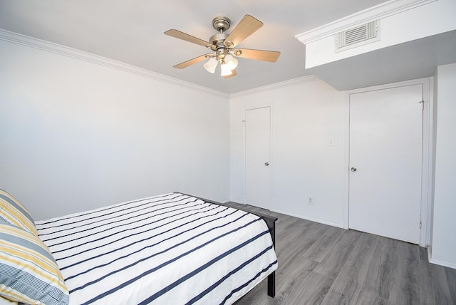 bedroom featuring hardwood / wood-style floors, ceiling fan, and crown molding