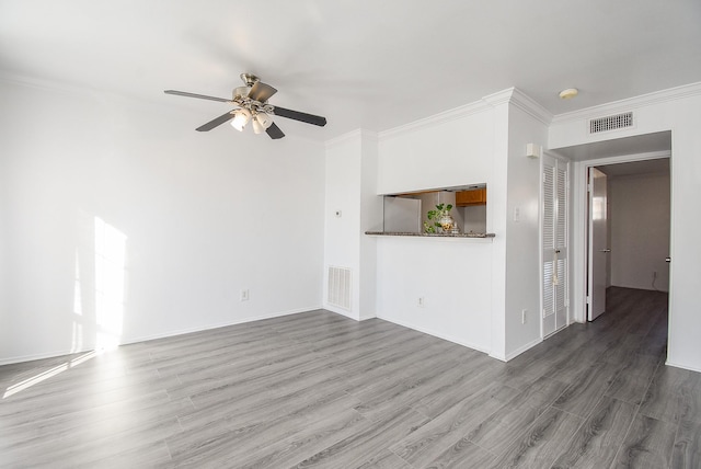 unfurnished living room with ceiling fan, crown molding, and dark wood-type flooring