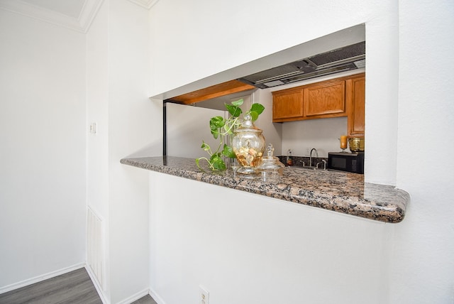 bar with crown molding, dark stone counters, and dark wood-type flooring