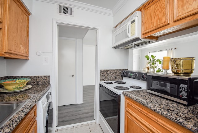 kitchen with ornamental molding, white appliances, dark stone countertops, washer / clothes dryer, and light tile patterned flooring