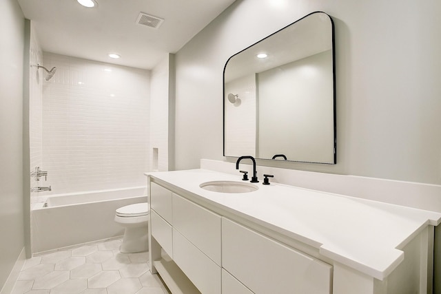 full bathroom with tile patterned floors, vanity, tiled shower / bath, and toilet