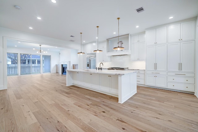 kitchen featuring decorative light fixtures, white cabinetry, built in fridge, and light hardwood / wood-style floors