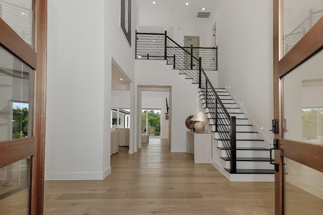 entryway with light wood-type flooring and a high ceiling