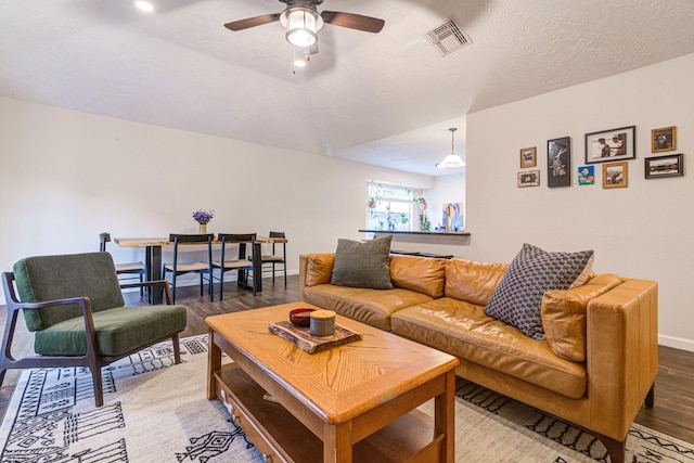 living room featuring ceiling fan, wood-type flooring, and a textured ceiling