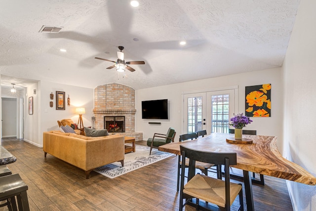 living room featuring lofted ceiling, dark wood-type flooring, french doors, ceiling fan, and a textured ceiling