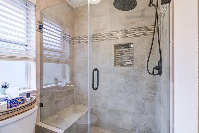 bathroom with plenty of natural light, a shower with door, and toilet