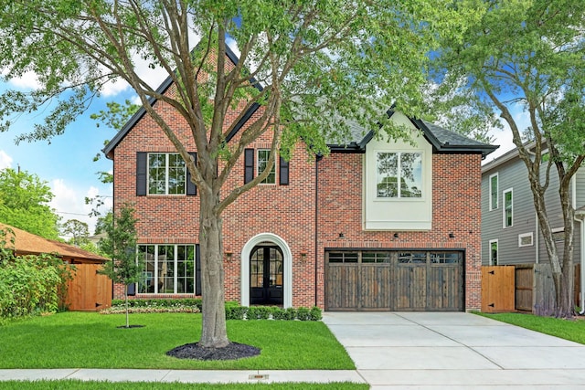 tudor-style house with french doors, a front lawn, and a garage